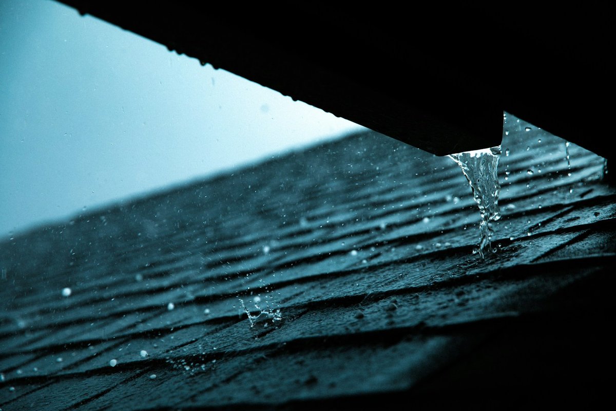 Rain running off the edge of an asphalt shingle roof